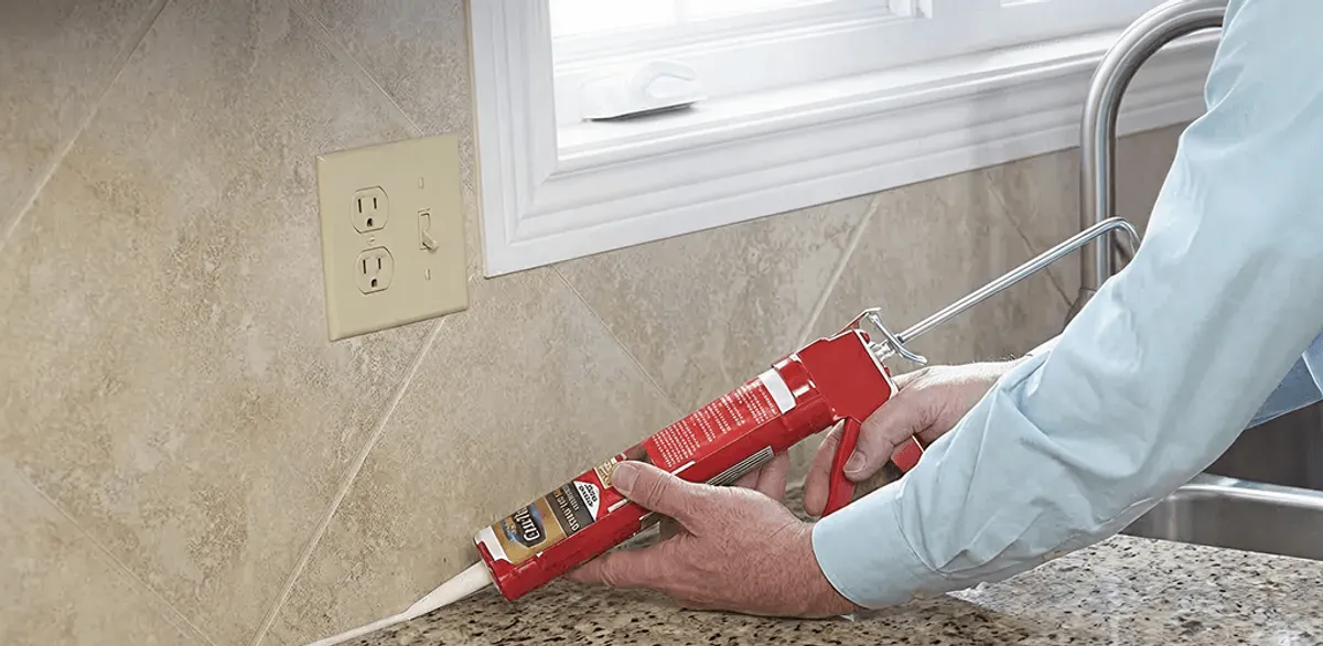 Handyman applying caulk along a kitchen backsplash and countertop seam in Henderson, NV